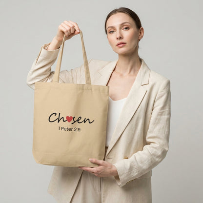 Model holding a natural cotton tote bag printed with “Chosen” (red heart accent) and “1 Peter 2:9” beneath.