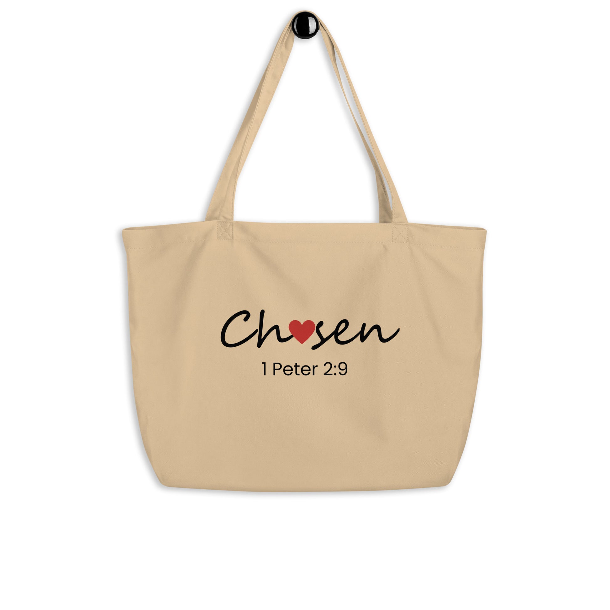 Large natural cotton tote bag hanging on a hook featuring “Chosen” with a red heart detail and “1 Peter 2:9” below.