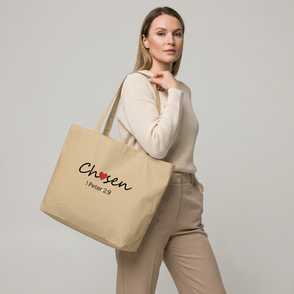 Model holding a natural large cotton tote bag printed with “Chosen” (red heart accent) and “1 Peter 2:9” beneath.