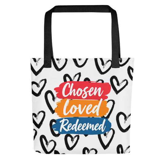 Front view of a white tote bag with black handles, black heart pattern, and stacked brushstroke text reading "Chosen," "Loved," and "Redeemed."