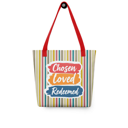 Striped tote bag hanging on a hook with red handles and “Chosen Loved Redeemed” in white script on red, orange, and blue brushstroke shapes.