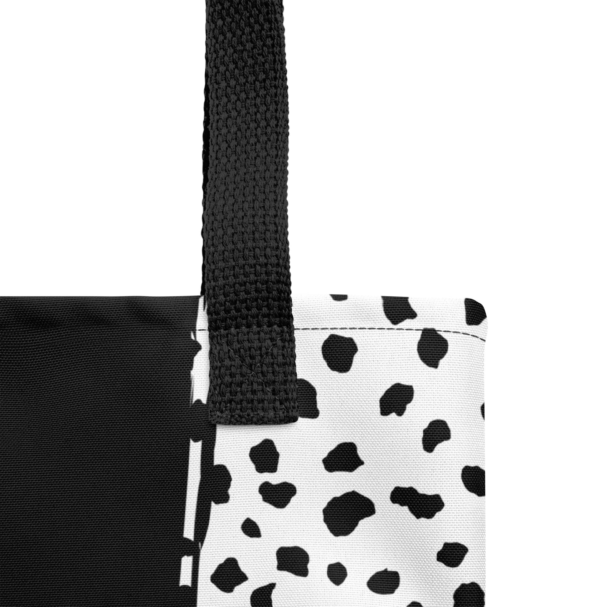 Close-up of the tote fabric and black strap, highlighting the stitching, textured canvas, and spotted color-block design in black and white.