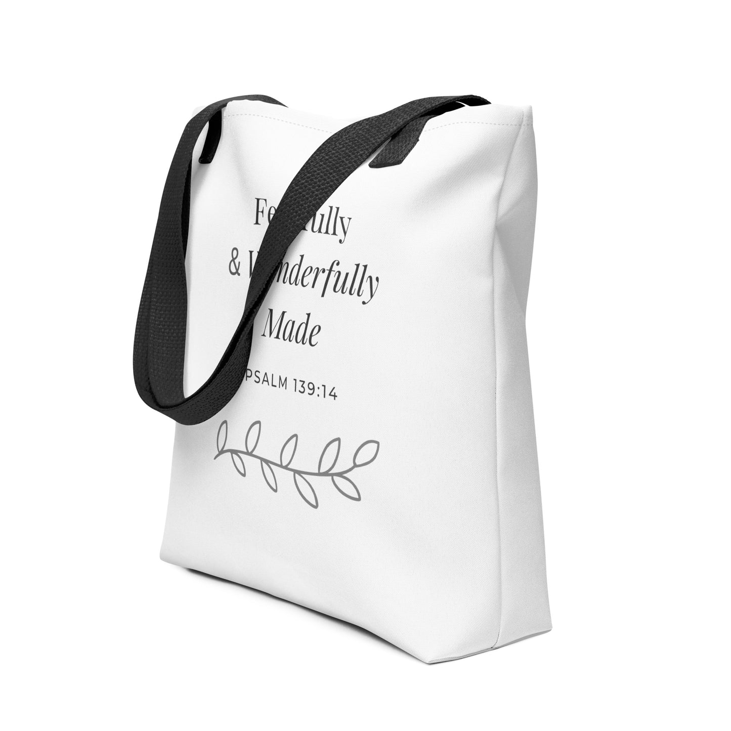 Angled view of a white tote bag with black handles featuring “Fearfully & Wonderfully Made,” “Psalm 139:14,” and a leaf vine design in dark gray.