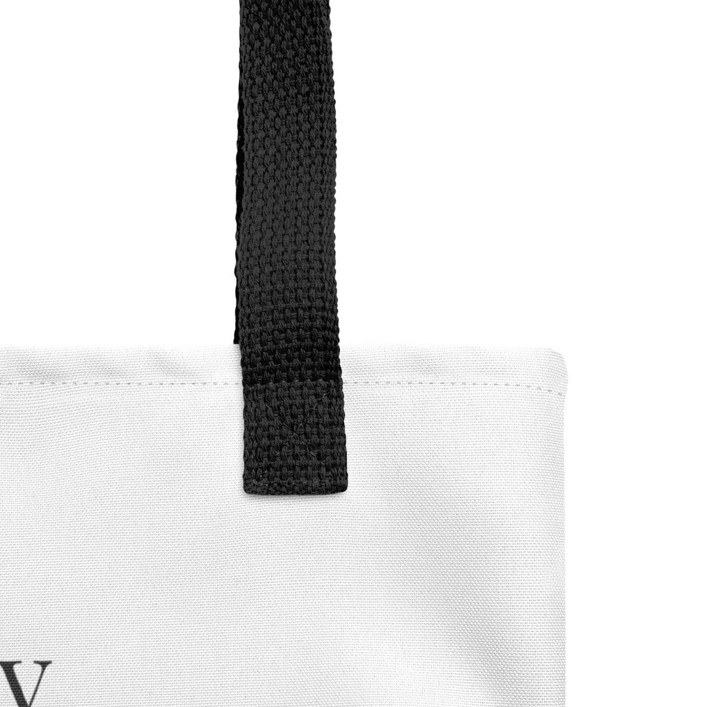 Close-up of the white tote fabric and black strap, highlighting the stitching, textured canvas, and strap weave detail.