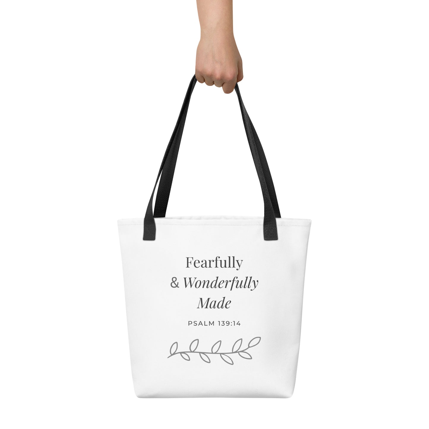White tote bag held in hand with black handles featuring “Fearfully & Wonderfully Made,” “Psalm 139:14,” and a leaf vine design in dark gray.