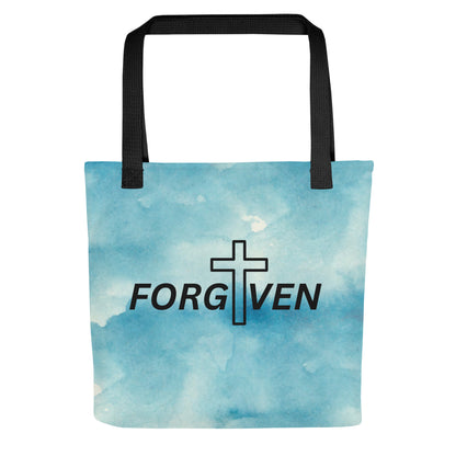 Front view of a tote bag with black straps, a blue watercolor background, and the word “FORGIVEN” with a cross integrated into the design.