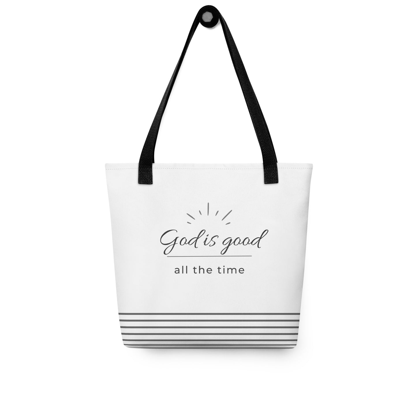 White tote bag hanging on a hook with “God is good all the time” in dark gray and gray horizontal stripes at the bottom.