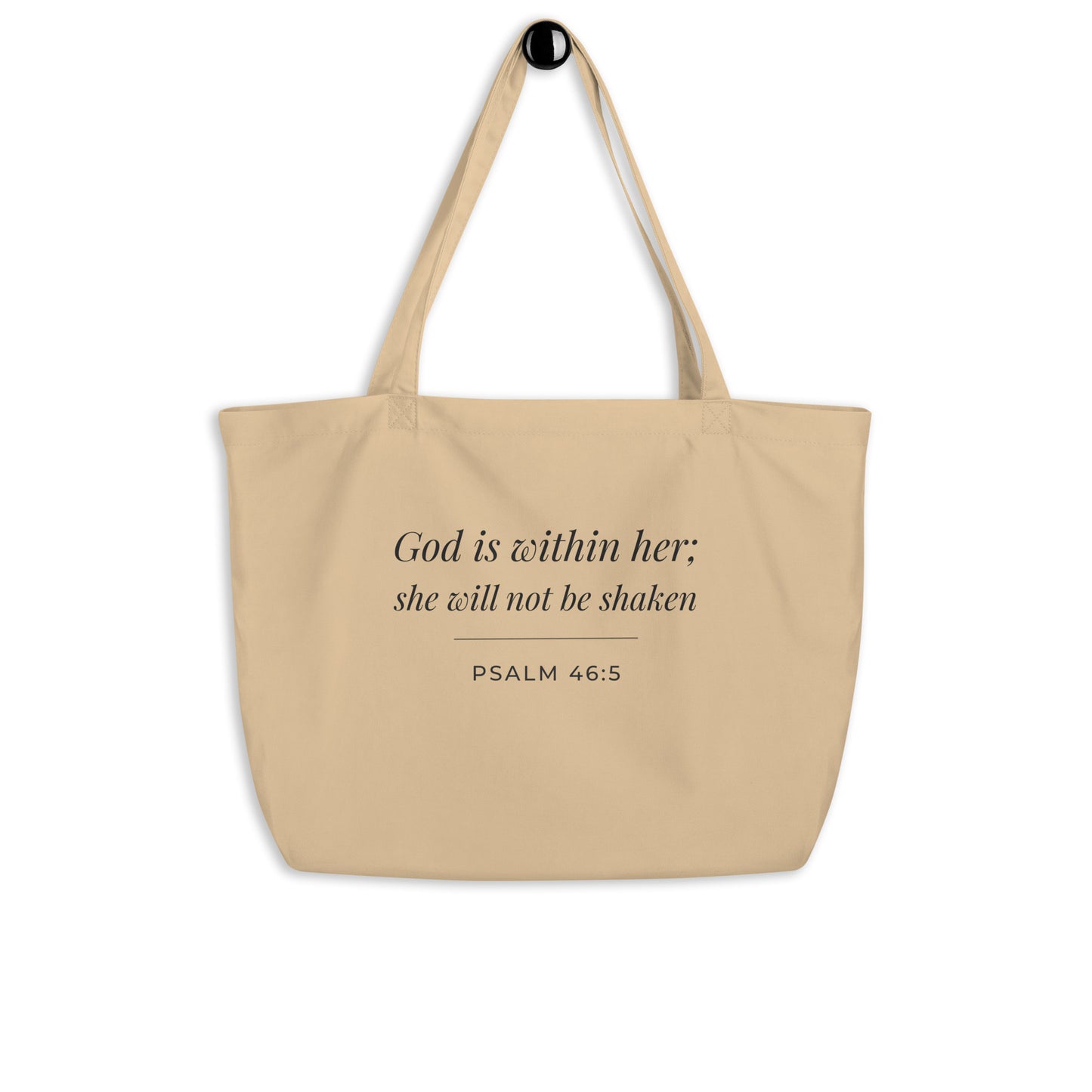 Natural cotton Christian tote bag hanging on a hook, featuring beige straps and a minimalist Psalm 46:5 faith design.