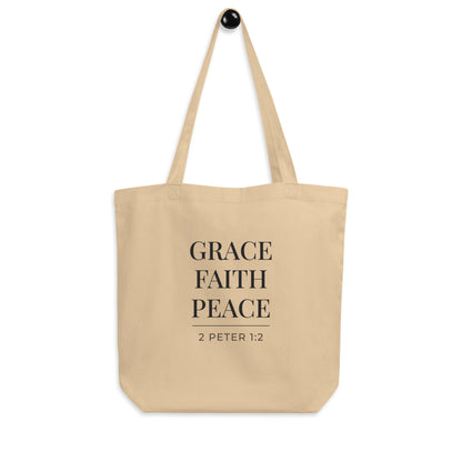 Cotton tote bag hanging on a hook with the words “Grace Faith Peace” and the scripture reference “2 Peter 1:2.”