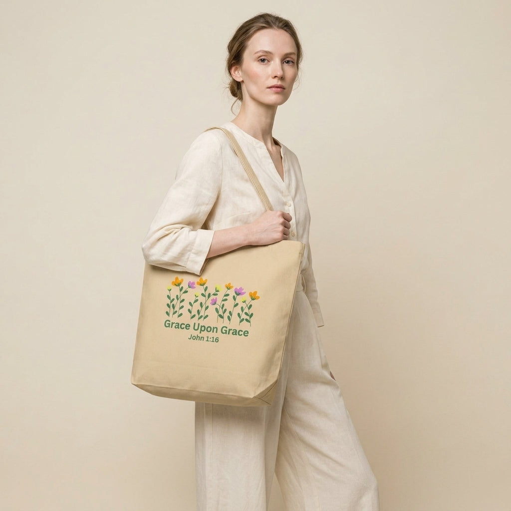Model carrying a beige cotton tote bag with floral artwork and the text “Grace Upon Grace” and “John 1:16.”