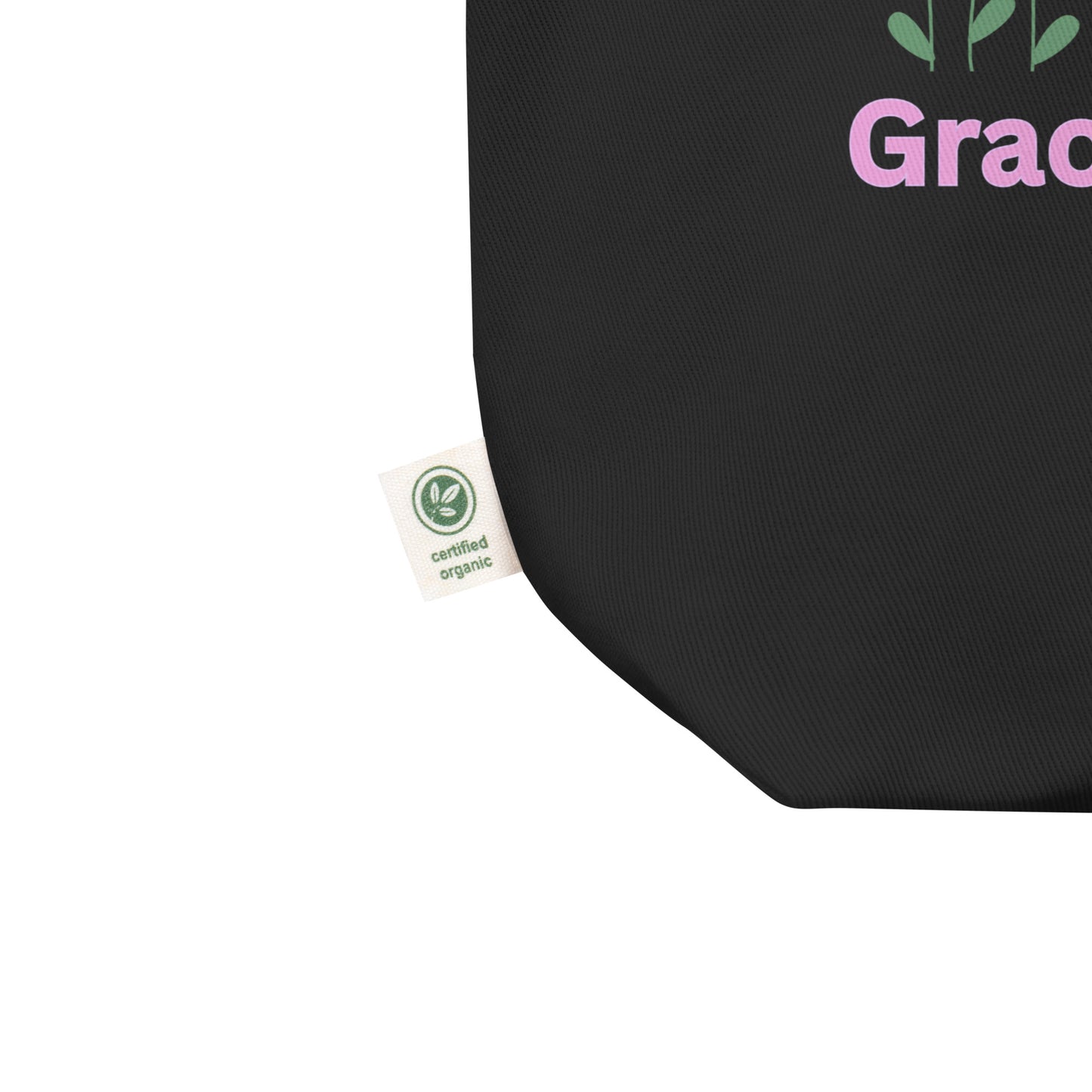 Close-up of the black cotton tote fabric, showing the textured weave and a side “certified organic” tag detail.