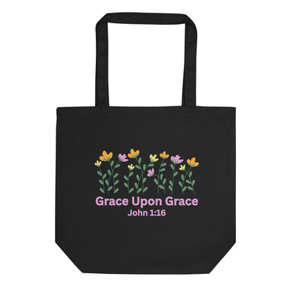 Black cotton tote bag with a colorful floral graphic above “Grace Upon Grace” and “John 1:16” in pink text.