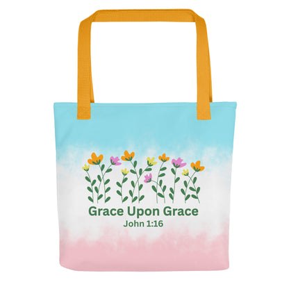 Front view of a pastel blue and pink Christian tote bag with yellow handles, floral artwork, and the text “Grace Upon Grace John 1:16.”