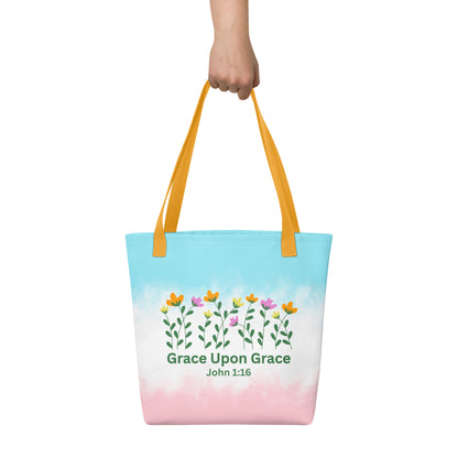 Person holding a pastel Christian tote bag with yellow handles, floral artwork, and the inspirational Bible verse design “Grace Upon Grace John 1:16.”