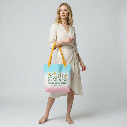 Model carrying a pastel Christian tote bag with yellow handles, floral details, and the Bible verse phrase “Grace Upon Grace John 1:16.”
