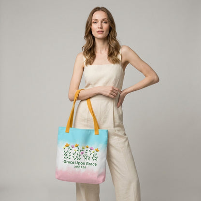 Model carrying a pastel Christian tote bag with yellow handles, floral details, and the Bible verse phrase “Grace Upon Grace John 1:16.”