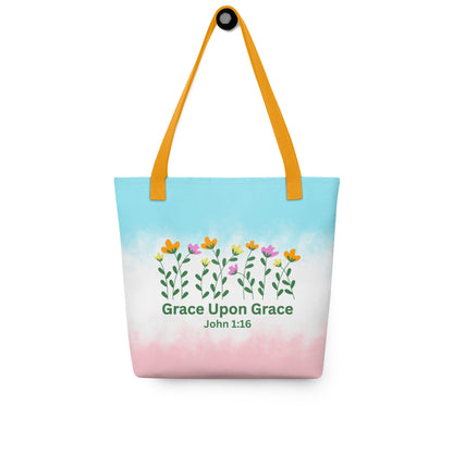 Christian tote bag hanging on a hook, featuring yellow straps, pastel blue and pink colors, flowers, and “Grace Upon Grace John 1:16” design.