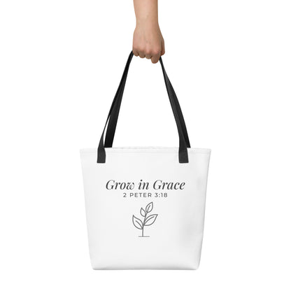 White tote bag held in hand with black handles featuring “Grow in Grace,” “2 Peter 3:18,” and a plant design in dark gray.