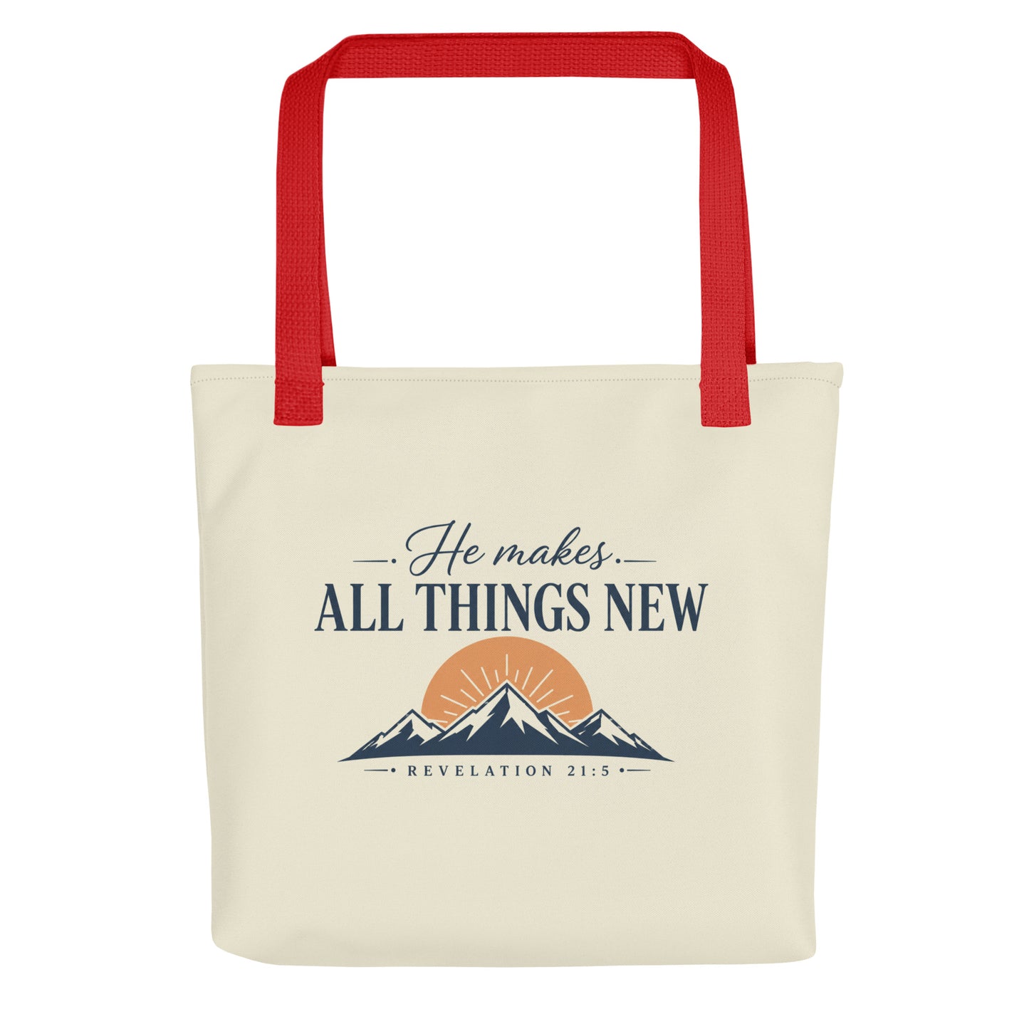 Front view of a cream Christian tote bag with red handles, mountain artwork, a sunrise, and the text “He Makes All Things New Revelation 21:5.”