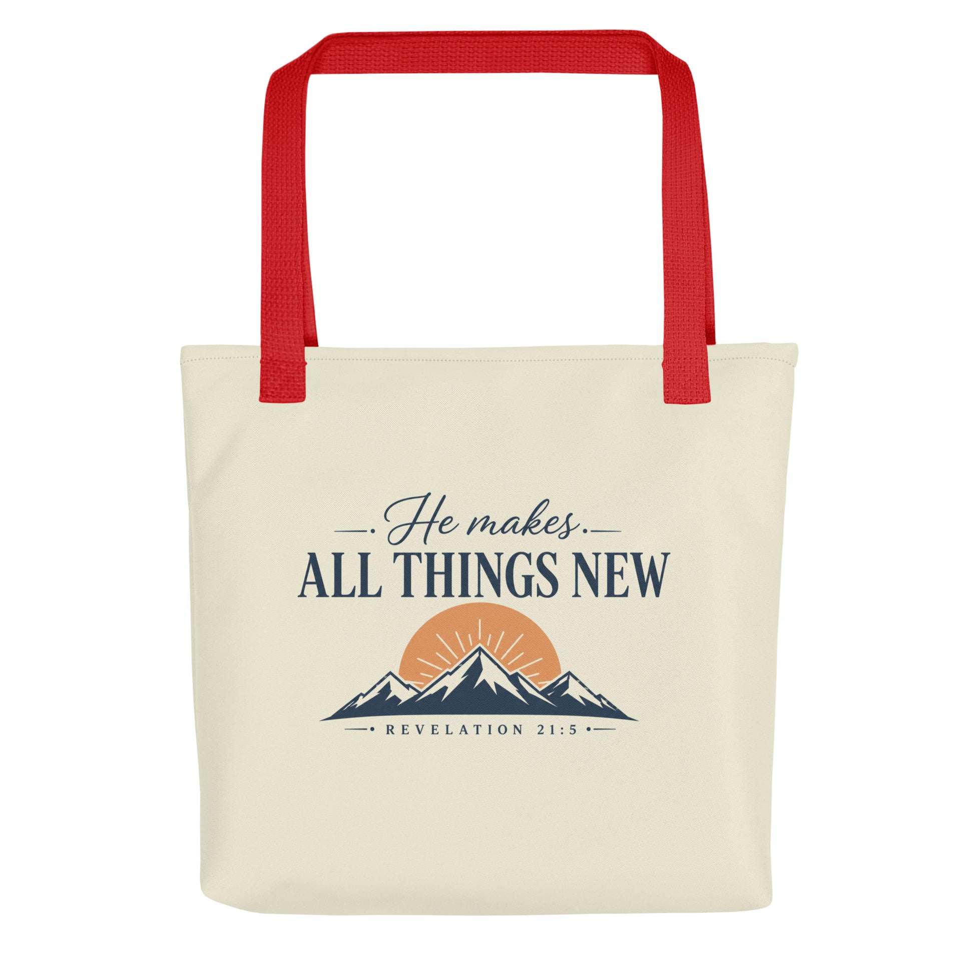 Front view of a cream Christian tote bag with red handles, mountain artwork, a sunrise, and the text “He Makes All Things New Revelation 21:5.”