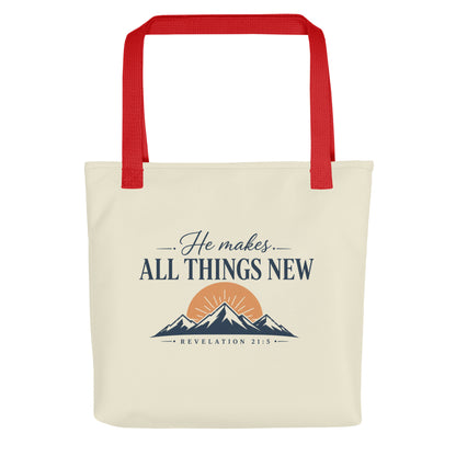 Front view of a cream Christian tote bag with red handles, mountain artwork, a sunrise, and the text “He Makes All Things New Revelation 21:5.”