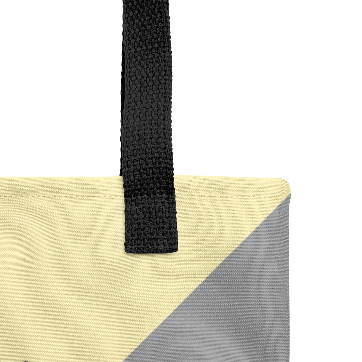 Close-up of the tote’s black strap and reinforced stitching on the top edge, with cream and gray color-block fabric visible.