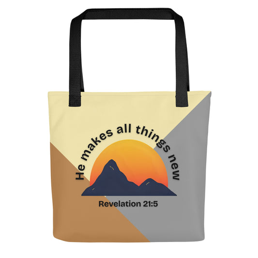 Front view of a color-block tote bag with black straps, featuring a mountain-and-sun graphic and the text “He makes all things new” with “Revelation 21:5” underneath.