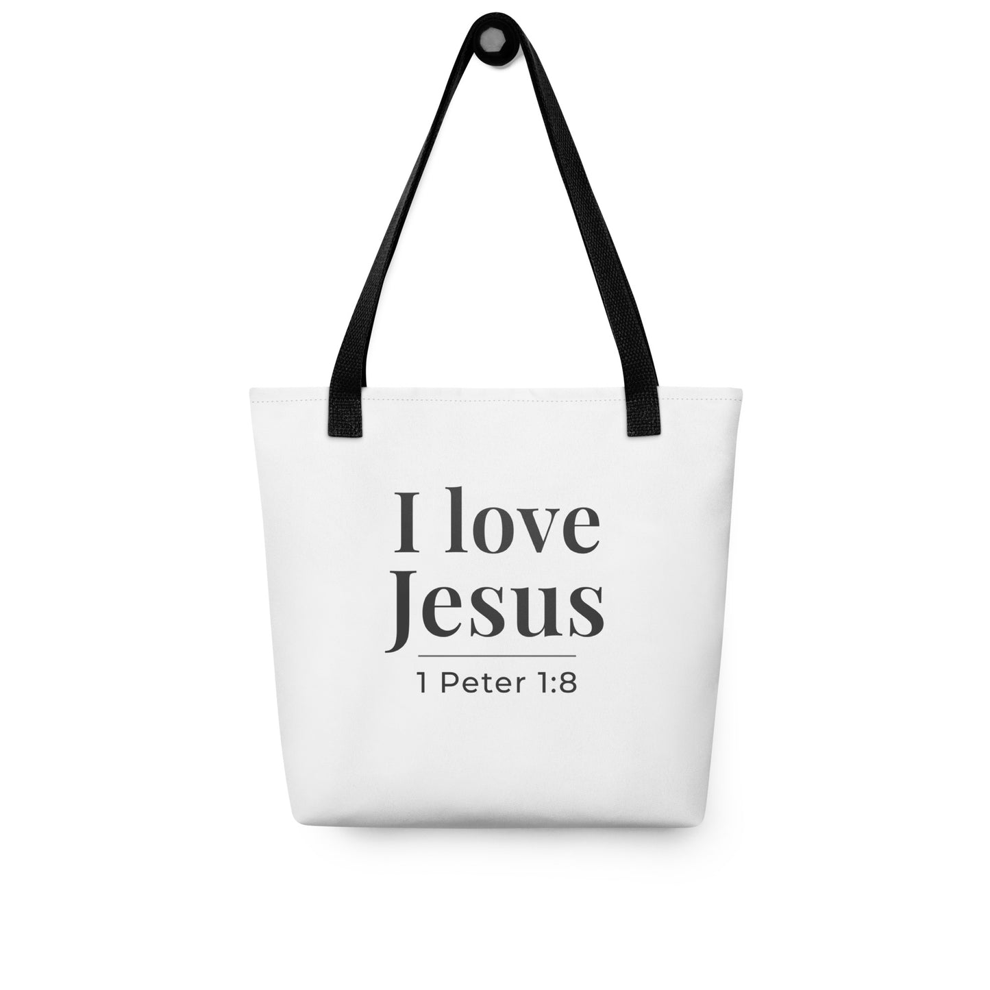 White tote bag hanging on a hook printed with “I love Jesus” and “1 Peter 1:8” in dark gray.