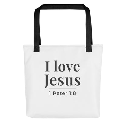 White tote bag with black handles featuring the phrase “I love Jesus” and “1 Peter 1:8” in dark gray text.