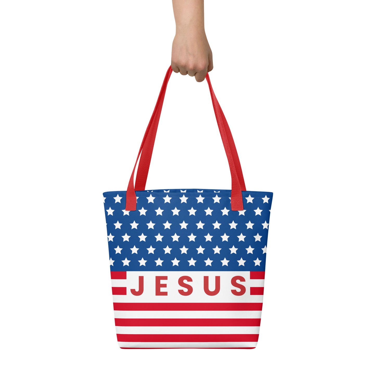 Person holding a Christian American flag tote bag with red handles, patriotic stars and stripes, and “Jesus” lettering.