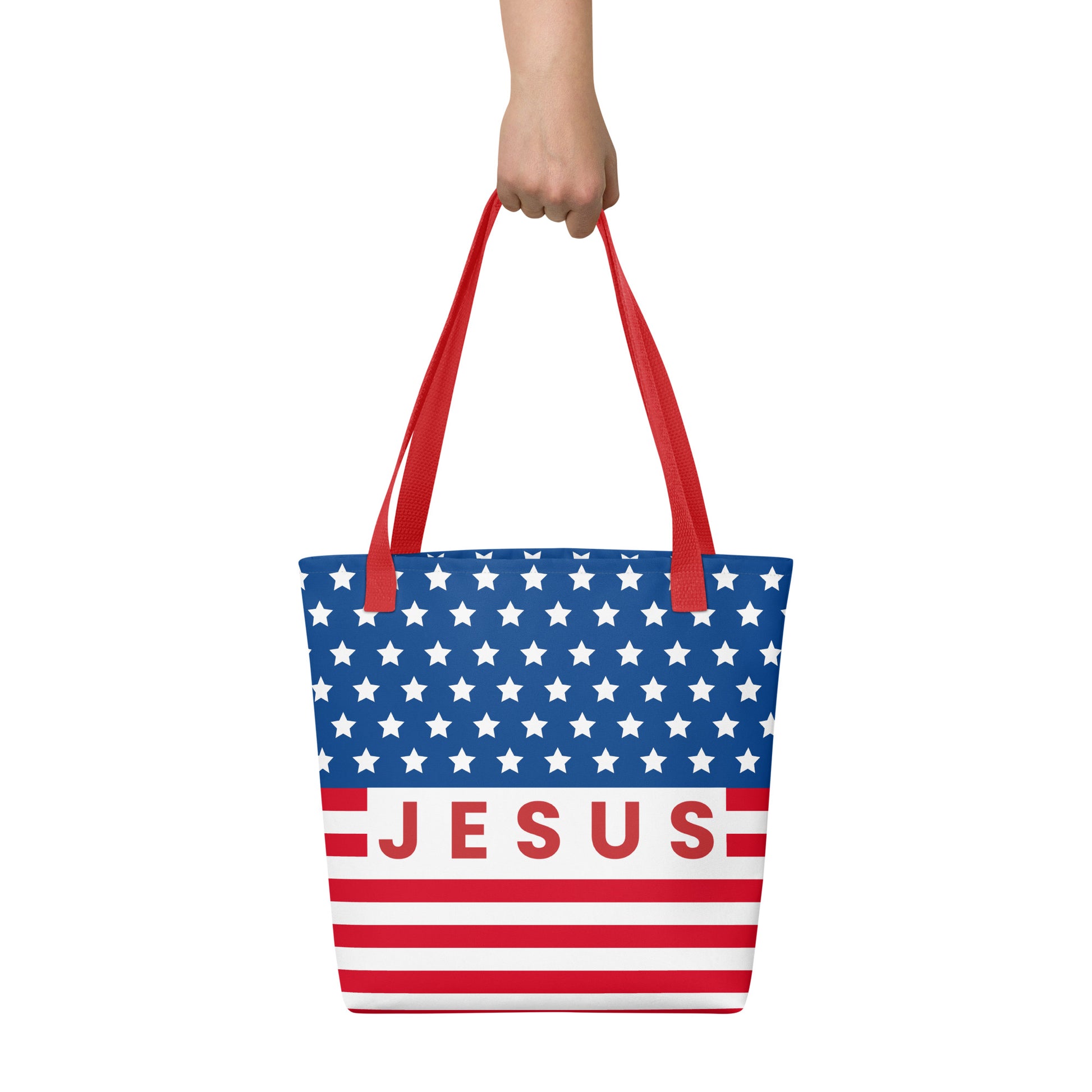Person holding a Christian American flag tote bag with red handles, patriotic stars and stripes, and “Jesus” lettering.