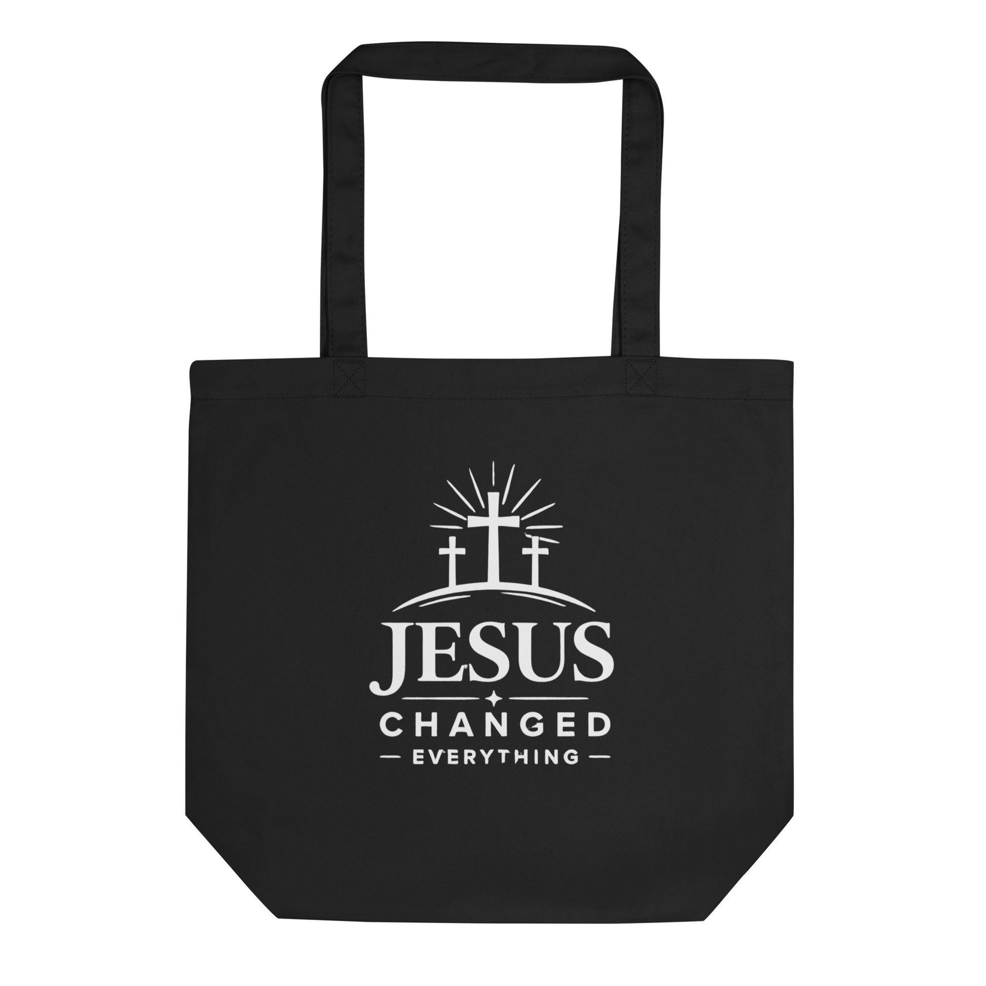 Front view of a black cotton Christian tote bag with matching black handles and a white “Jesus Changed Everything” cross design.