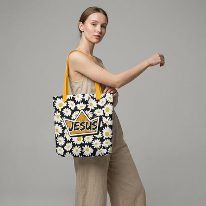 Model carrying a black daisy-print tote with mustard yellow straps, featuring a crown-shaped “JESUS” design on the front.