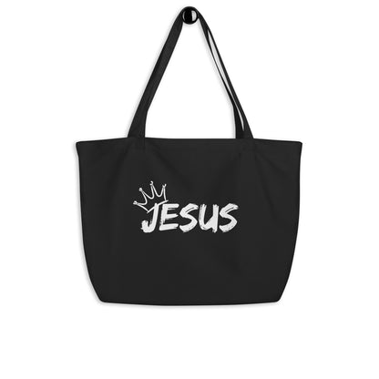 Large black cotton tote bag hanging on a hook featuring a white “JESUS” design with a crown graphic above it.