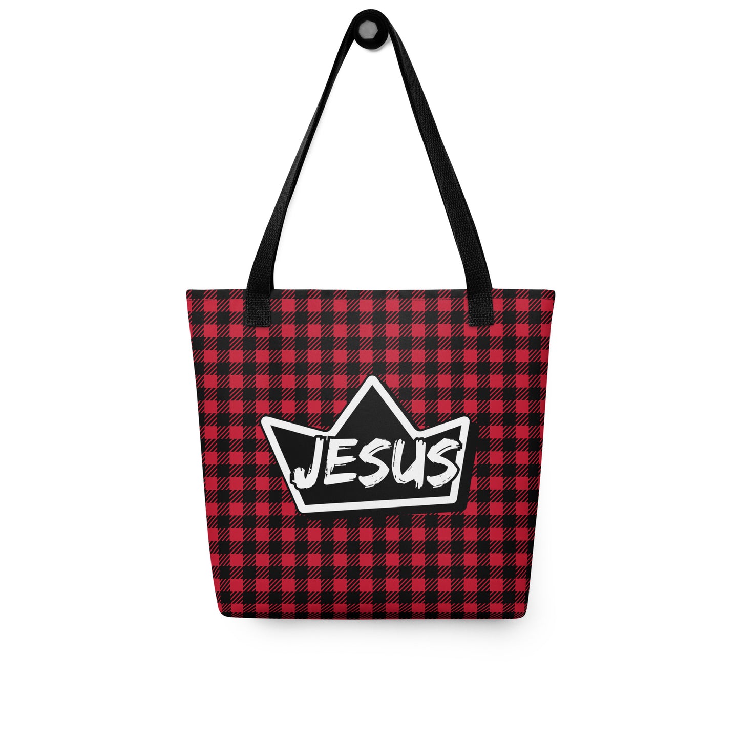 Red and black plaid tote bag with black straps hanging on a hook, displaying a black crown graphic with “JESUS” in white text.