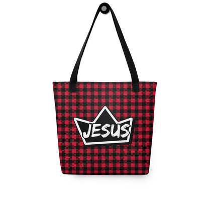Red and black plaid tote bag with black straps hanging on a hook, displaying a black crown graphic with “JESUS” in white text.