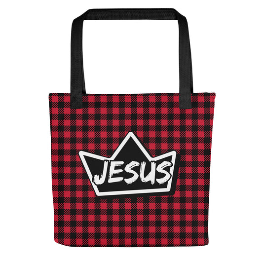 Front view of a red and black buffalo plaid tote bag with black straps, featuring a black crown graphic with the word “JESUS” in white lettering.