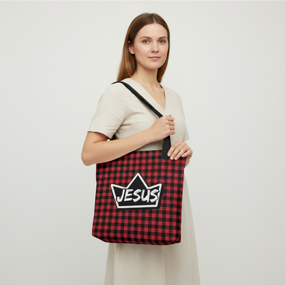 Model carrying a red and black plaid tote with black straps, featuring a crown-shaped “JESUS” design on the front.