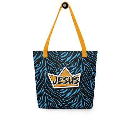 Tote bag hanging on a hook with yellow handles, a blue-and-black zebra pattern, and a crown “JESUS” graphic on the front.