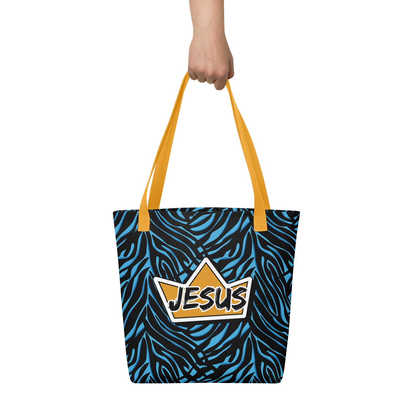 Tote bag held in hand with yellow straps, blue-and-black zebra print, and a gold crown “JESUS” design.