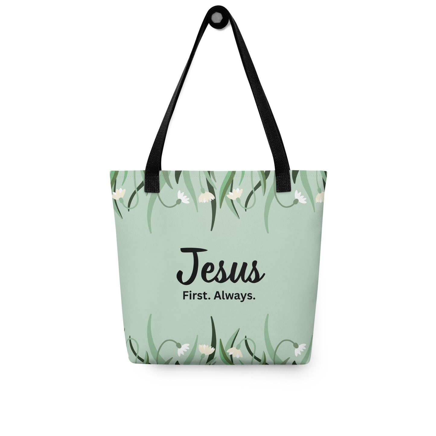 Mint green floral tote bag with black straps hanging on a hook, displaying the “Jesus. First. Always.” design.