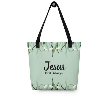 Mint green floral tote bag with black straps hanging on a hook, displaying the “Jesus. First. Always.” design.