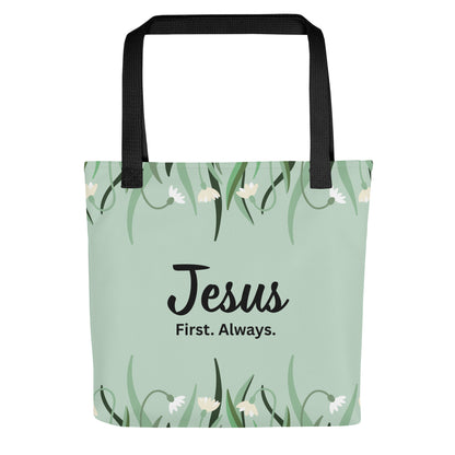 Front view of a mint green floral tote bag with black straps featuring the phrase “Jesus. First. Always.” in black lettering.