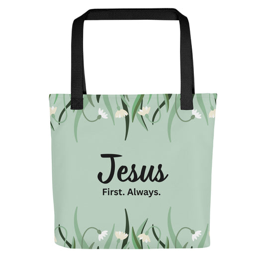 Front view of a mint green floral tote bag with black straps featuring the phrase “Jesus. First. Always.” in black lettering.
