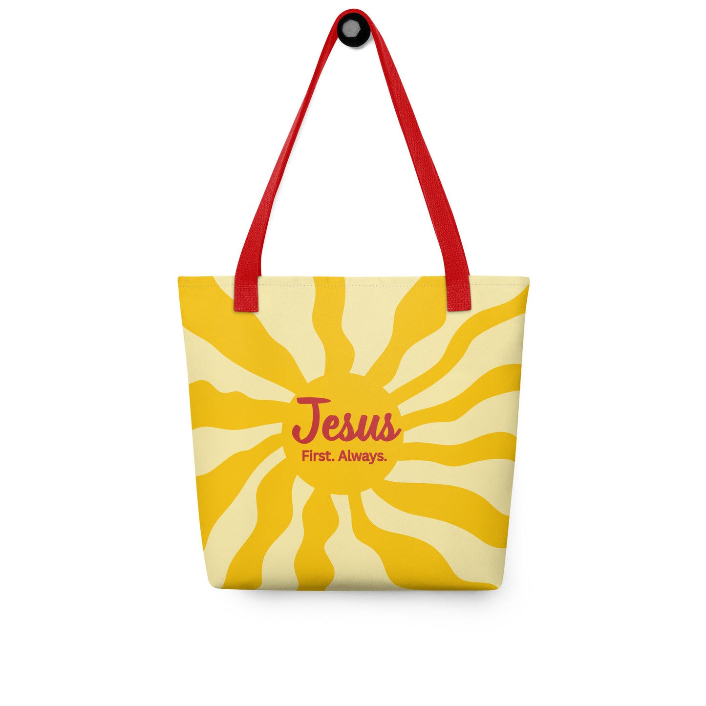 Tote bag hanging on a hook with red handles, yellow sunburst background, and “Jesus First. Always.” text.