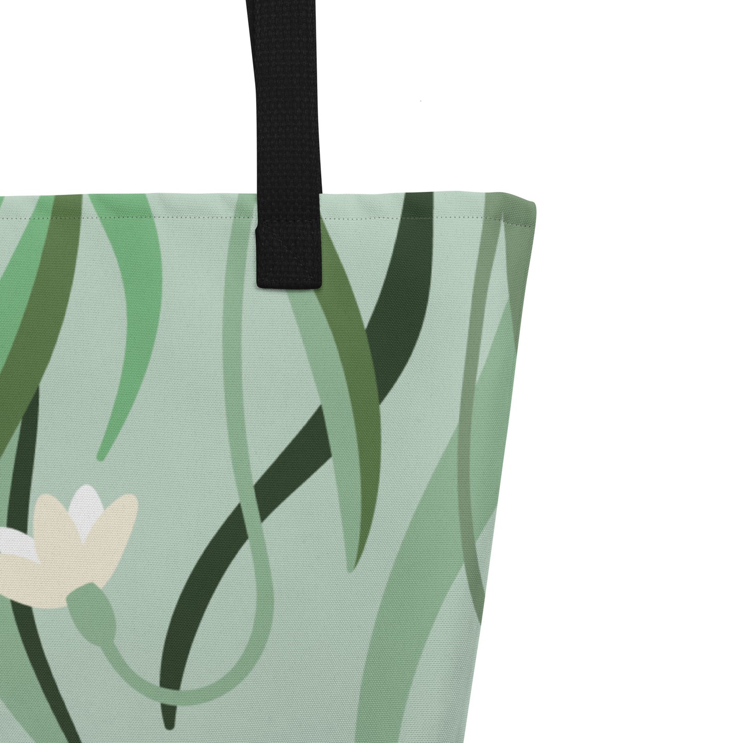 Close-up of black woven handle and stitched top edge on the sage green fabric with leafy floral print.