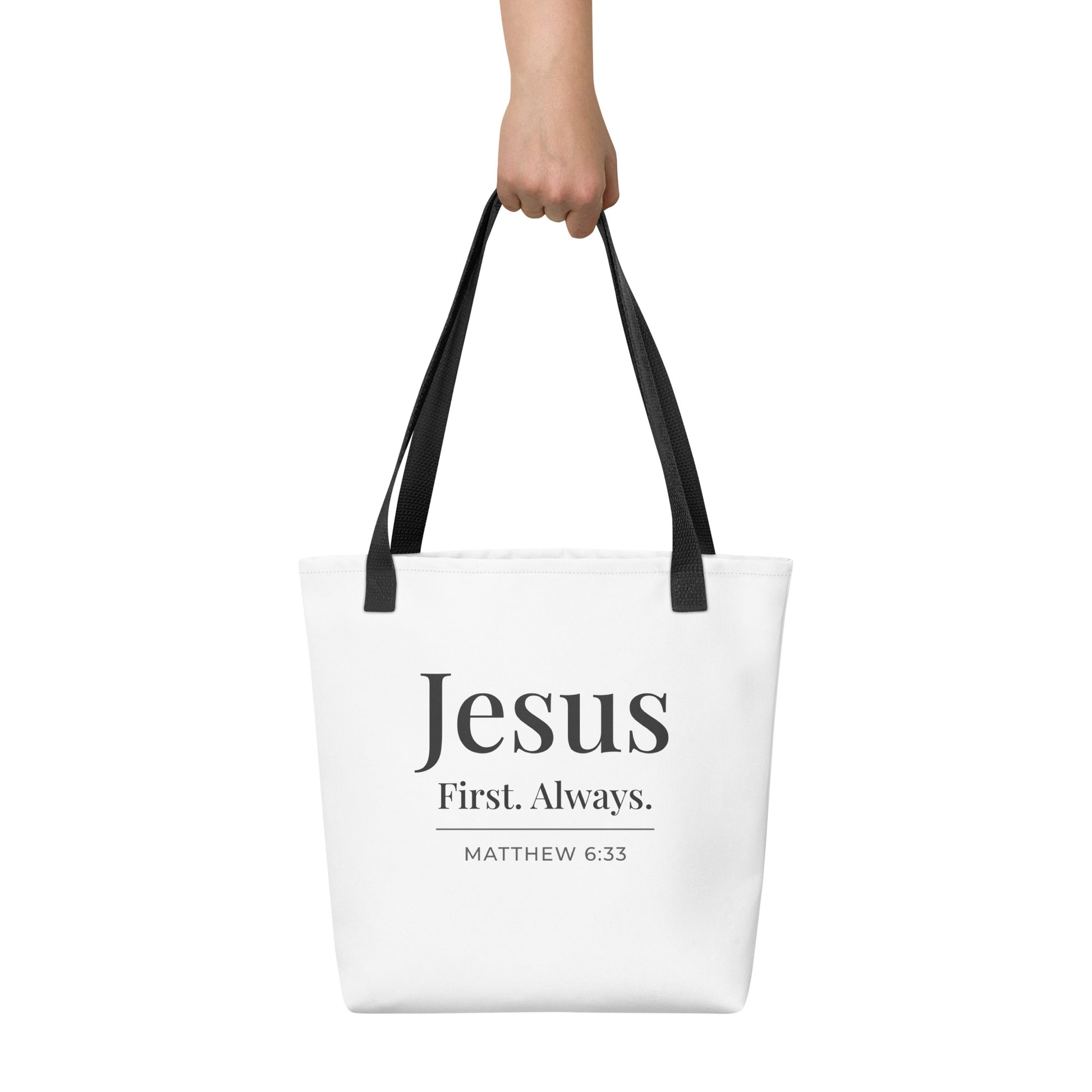 White tote bag held in hand featuring “Jesus First. Always.” in dark gray text with “Matthew 6:33” beneath.