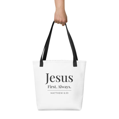 White tote bag held in hand featuring “Jesus First. Always.” in dark gray text with “Matthew 6:33” beneath.