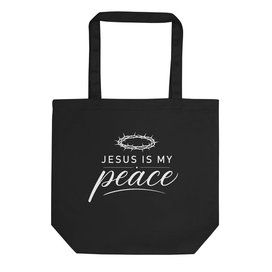 Front view of a black cotton Christian tote bag with matching black handles and a white “Jesus Is My Peace” crown of thorns design.