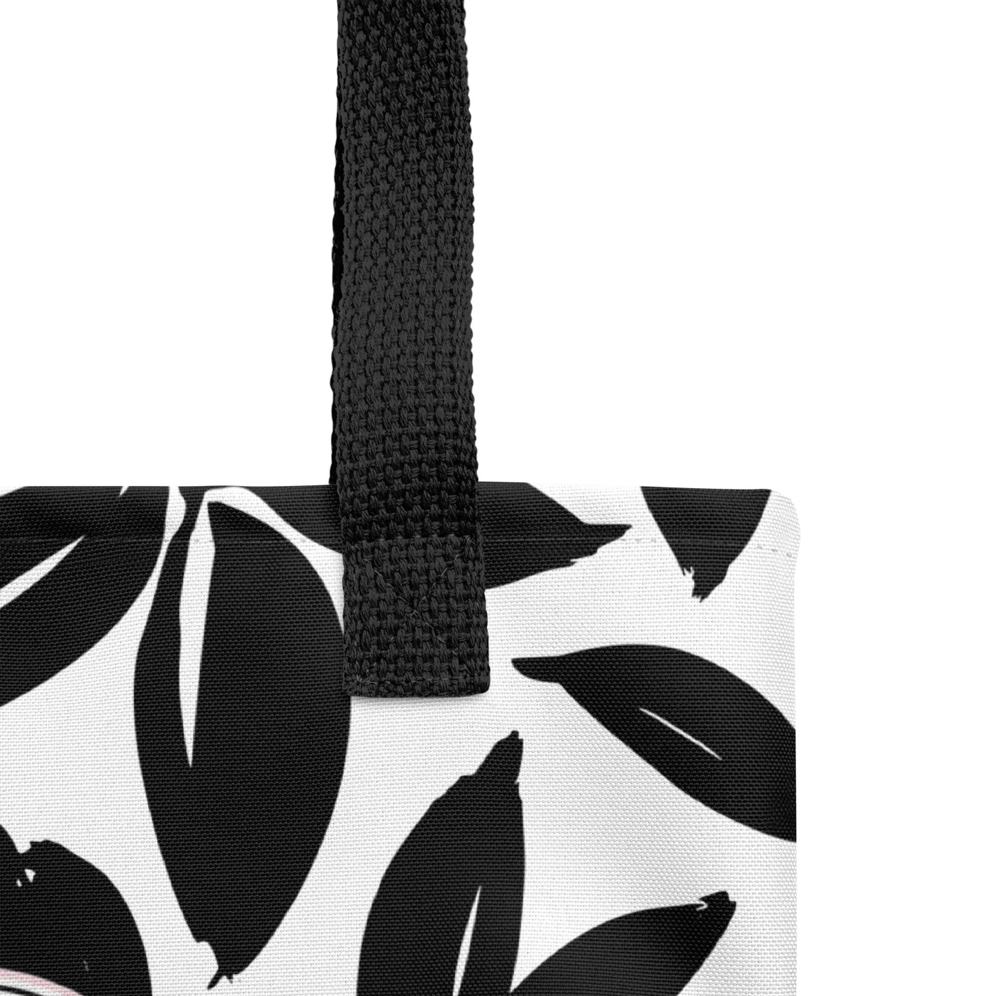 Close-up of a black and white Christian tote bag showing the black woven handle, fabric texture, and bold leaf pattern.